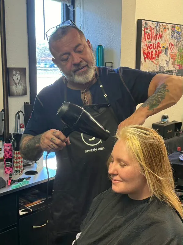 Master colorist Rob Maggart blow-drying a client's hair in his Colorado Springs studio